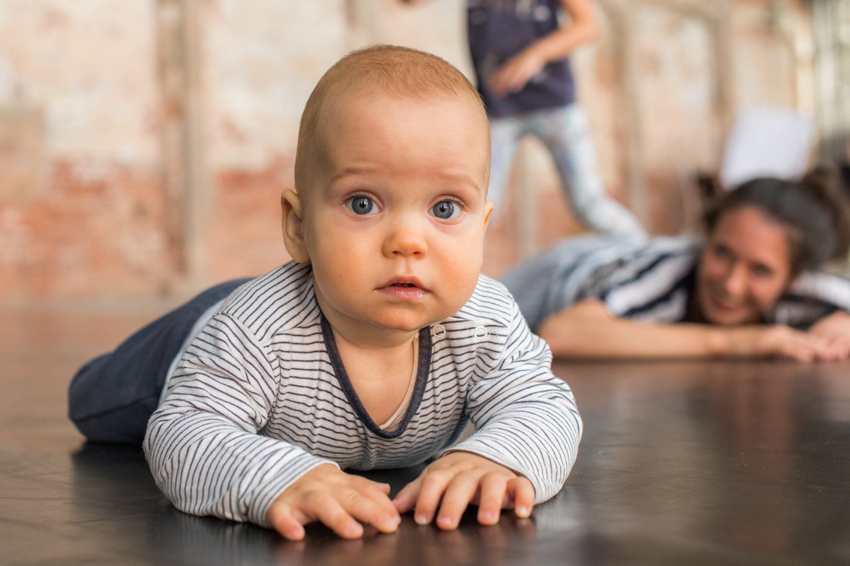 Zdjęcie niemowlaka leżacego na brzuchu i podpierającego się rączkami
