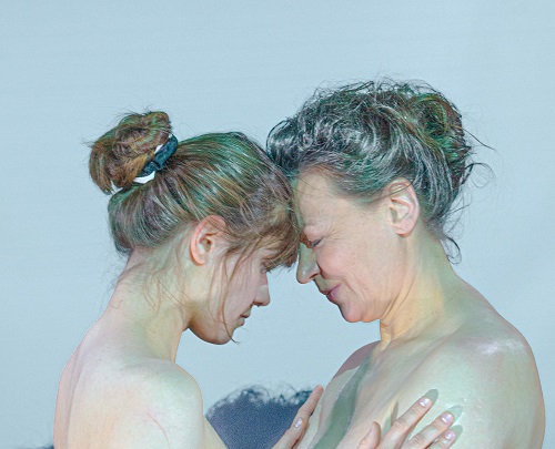 Dwie kobiety, młodsza i starsza, naprzeciwko siebie, dotykają się czołami.