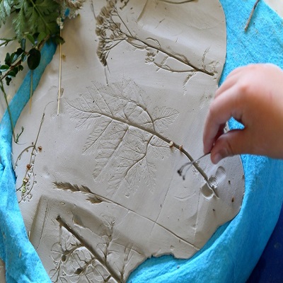 Kawałek gliny, w którym są odciśnięte liście.