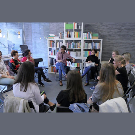 Zdjęcie ze spotkania Zamkowego Klubu Książki Ukraińskiej. Uczestnicy siedzą na krzesłach ustawionych w kształcie koła. W tle wypełnione książkami regały Księgarni Bookowski.