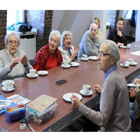 Uczestnicy warsztatów siedzą przy brązowym stole, na którym leżą kolorowe flamastry i pudełko z guzikami