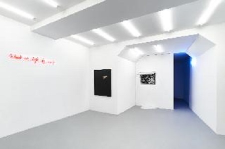 Zdjęcie z wystawy. Minimalistyczna biała przestrzeń galerii, na ścianach wiszą obrazy.