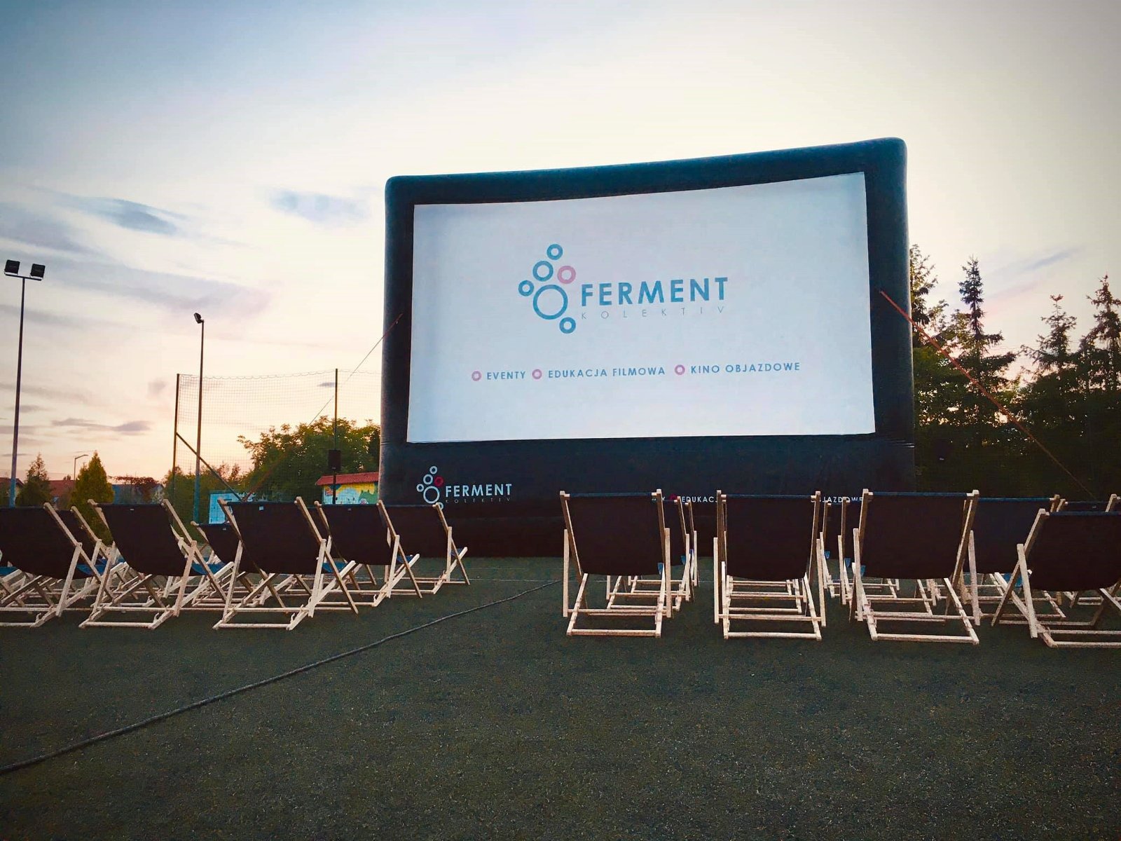 Duży ekran do wyświetlania filmów, a przed nim leżaki
