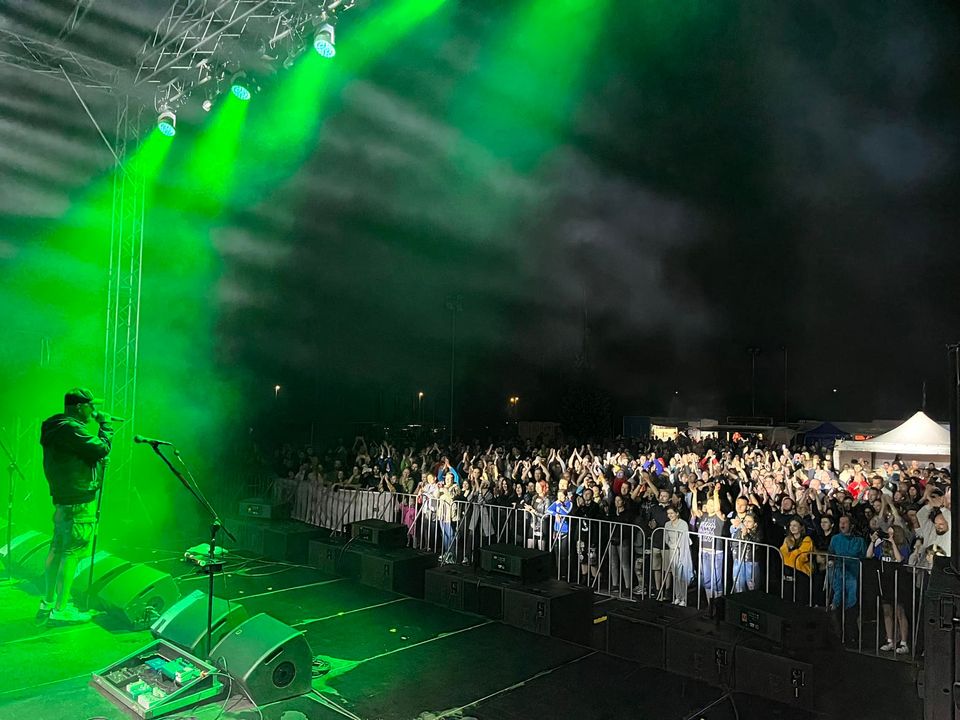 Mężczyzna na scenie w zielnym świetle, przed nimi publiczność.