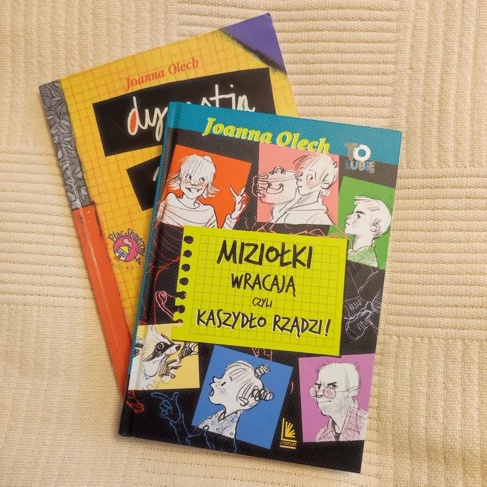 Dwie ksiązki z kolorowymi okładkami leżą na sobie po ukosie na beżowym miękkim tle.