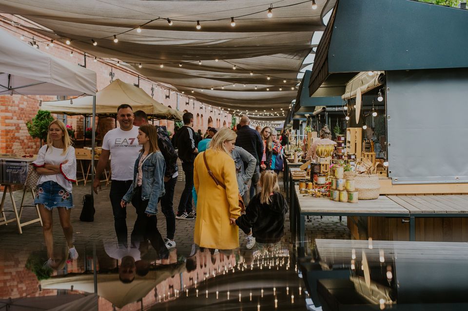 Ludzie chodzący pod zadaszonymi straganami.