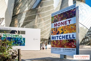Przed wejściem reklmay o wystawie w środku muzeum. W tle nowoczesne przeszkolne wejście do muzeum.