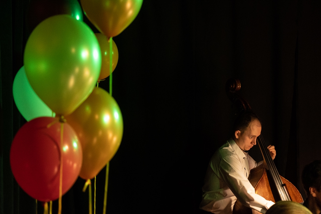 zdjęcie przedstawia po lewej stronie kolorowe balony, w prawym dolnym rogu muzyka grającego na kontrabasie
