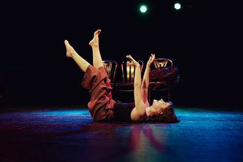 Na podłodze leżu kobieta, ma uniesione do góry ręce i nogi.