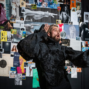 Zdjęcie mężczyzny w czarnym stroju na tle kolorowych zdjęć.