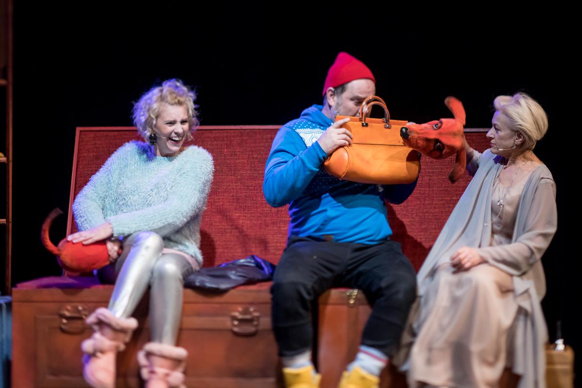 Zdjęcie ze spektaklu: trzy osoby siedzące na ławce. Mężczyzna trzyma przed sobą torebkę, zasłania się przed psem animowanym przez jedną z dwóch aktorek.