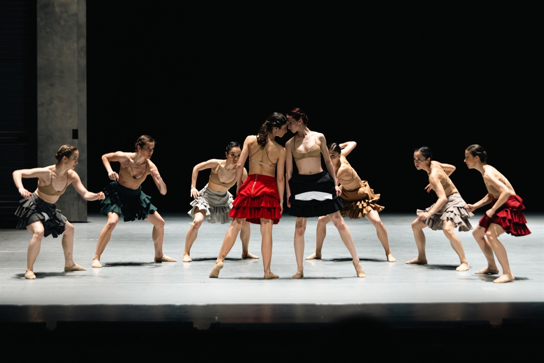 Scena ze spektaklu - tancerze na scenie, w środku dwie tancerki blisko siebie, dotykają się głowami.