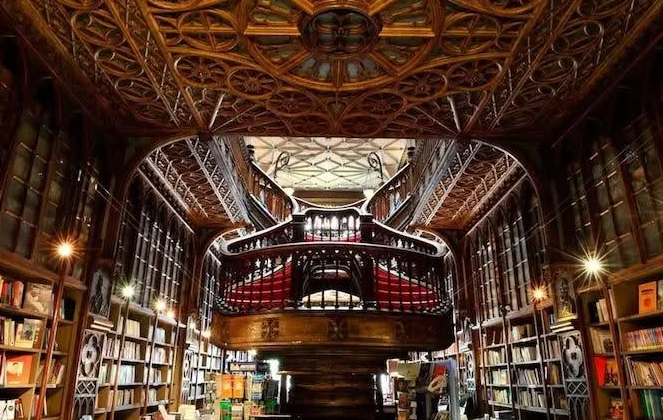 Wnętrze biblioteki wypełnionej książkami na drewnianych regałach. W centrum widoczne są schody.