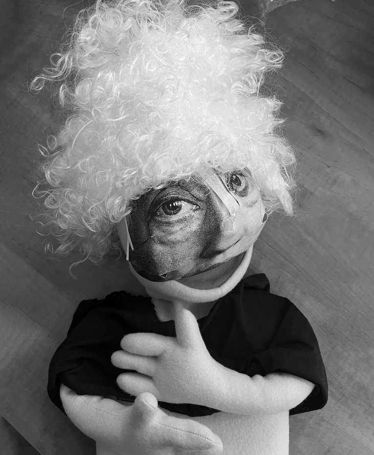 Zdjęcie szmacianej lalki z maską przypominającą kobietę, w peruce z kręconymi włosami.