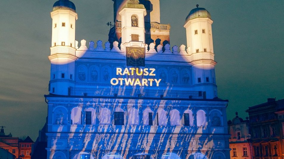 Podświetlony na niebiesko budynek renesansowego ratusza, na nim wyświetlony napis "Ratusz otwarty"
